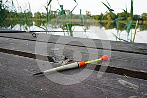 Fishing float, fishing bobber on the wooden pier. Fishing rod and fishing equipment on the jetty. Fishing concept.