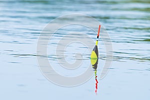 Fishing float on the water surface in close-up. Spring fishing on fresh water