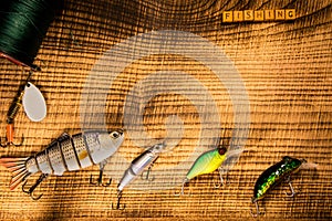 Fishing gear, artificial bait on a predator on a wooden background, top view with inscription fishing wobblers and