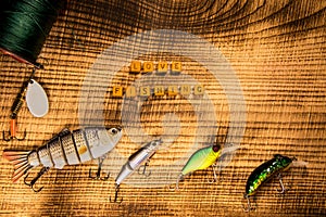 Fishing gear, artificial bait on a predator on a wooden background, top view with inscription love fishing wobblers and