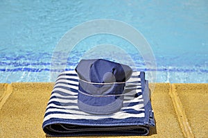 Fishing hat and striped towel in the pool