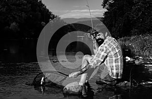 Fishing hobby and summer weekend. Bearded men fisher with fishing rod and net. Catching trout fish.