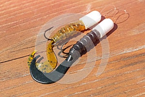 Fishing hooks with silicone on wooden background. Artificial bait for catching predatory fish.