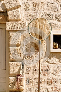 Fishing landing net against the background of a stone wall