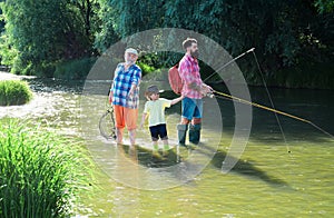 Fishing. Little boy fly fishing on a lake with his father and grandfather. Fishing in river. Young - adult concept.
