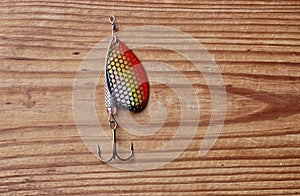 Fishing lure, bait spoon, equipment isolated on wooden background