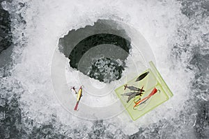 Fishing lures and accessories close up near the ice hole on the pond.