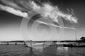 A fishing pier with strong horizontal lines contrasts against a summer sky marked by fluffy diagonal aligned clouds