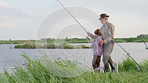 Fishing for pike, perch, carp. Skilled senior Fisherman and child boy with rod, spinning reel on river bank