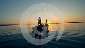 Fishing process of two anglers in a sunrise waterscape