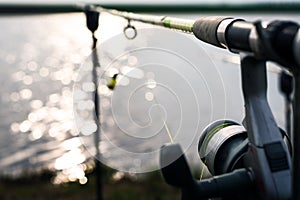 Fishing reel at the edge of the lake with focus on the wire