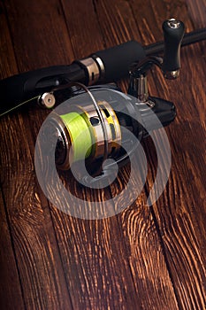 Fishing reel for a fishing rod with a green fishing line. Hobby. Sport. Wooden background