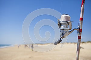 Fishing reel on rod detail with angling fishers at bottom on the