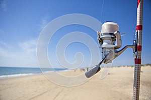 Fishing reel on rod detail with angling fishers at bottom on the