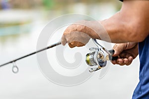 Fishing reel and rod in fisherman hand in a pond