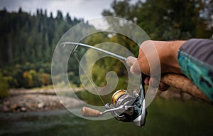 Fishing reel and spinning on stone, blurred background.