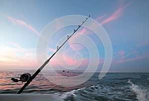 Fishing rod on charter fishing boat against pink sunrise sky on the Sea of Cortes in Baja Mexico photo
