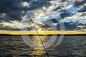 Fishing road silhouette during sunset. Fishing pole against ocean at sunset. Fishing rod in a saltwater boat during fishery day in