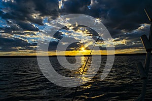 Fishing road silhouette during sunset. Fishing pole against ocean at sunset. Fishing rod in a saltwater boat during fishery day in