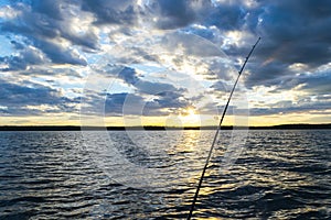 Fishing road silhouette during sunset. Fishing pole against ocean at sunset. Fishing rod in a saltwater boat during fishery day in