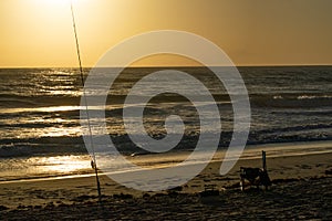 Fishing rod and beach chair on the beach at sunrise