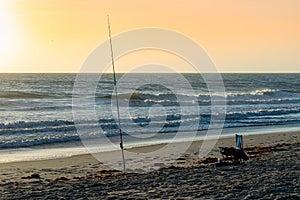 Fishing rod and beach chair on the beach at sunrise