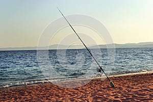 Fishing rod on beach shore at sunset