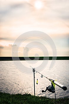 Fishing rod in beautiful sunset at the edge of the lake