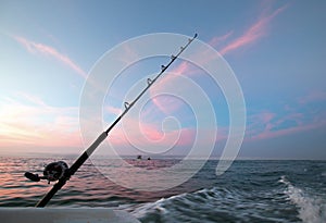 Fishing rod on charter fishing boat against pink sunrise sky on the Sea of Cortes in Baja Mexico