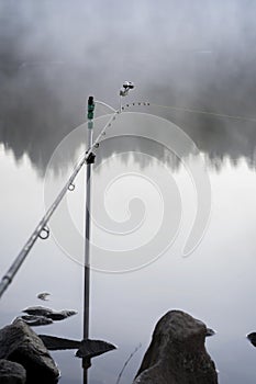 Fishing rod on foggy lake early in morning, dawn, first rays of the sun. Concept of seasons, environment, ecology