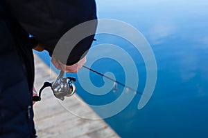 Fishing rod in the hands of a fisherman on the lake.