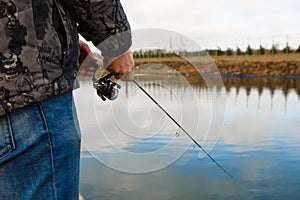 Fishing rod in the hands of a fisherman on the lake.