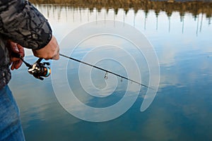 Fishing rod in the hands of a fisherman on the lake.