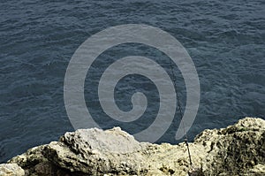 fishing rod isolated on the cliff by the blue water