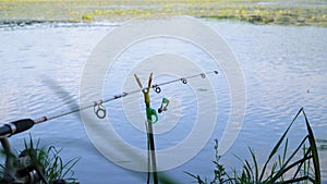 Fishing rod on the lake in summer day. Professional fishing rod waiting for bites on water river