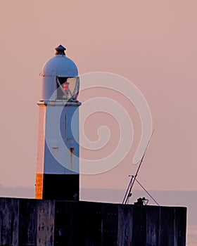 A fishing rod and lighthouse at dawn