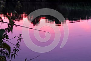 Fishing rod reflexing sunset in a river.