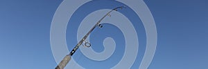 Fishing rod on sea beach on blue sky background