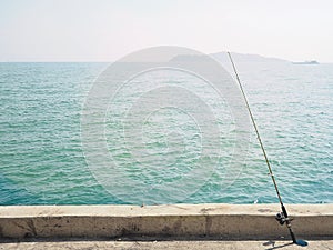 Fishing rod beside sea/ocean on summer.