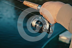 Fishing rod with a spinning reel in the hands of a fisherman.