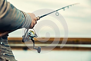 Fishing rod with a spinning reel in the hands of a fisherman photo