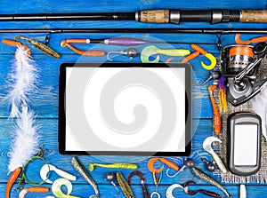 Fishing rod, tackles and fishing baits, reel on wooden board background with tablet computer isolated white screen, empty space photo
