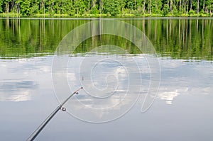 Fishing rod, water surface, float, day, reflection of clouds.