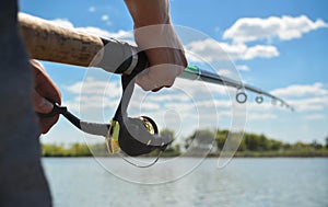 Fishing rod wheel close up in young man hands