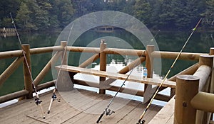 Fishing rods leaning against the hand rail on a wooden marine