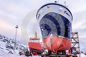 Fishing ships hulls in dockyard on maintenance during the winter time, port of Nuuk, Greenland