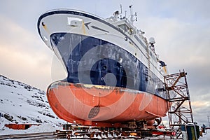 Fishing ships hulls in a dockyard on maintenance during the winter time, port of Nuuk, Greenland