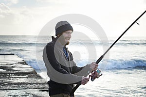 Fishing, smile and travel with man at beach for adventure, holiday and hobby break. Sunset, calm and patience with male