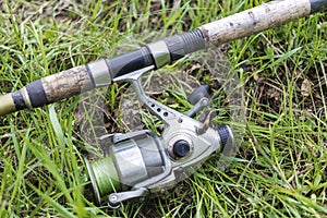 Fishing spinning lies on the grass. Fishing with a spinning reel. Close-up of fishing tackle