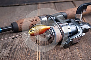 Fishing spinning reel and fishing lures on wooden table